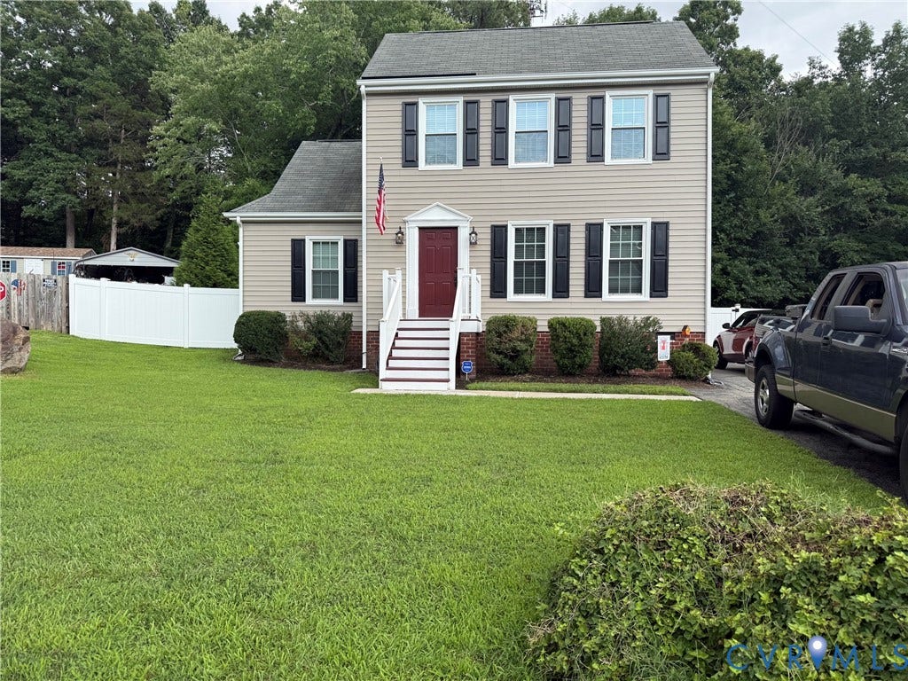 Two-story residence featuring light-colored siding, contrasting dark shutters, and a prominent red front door