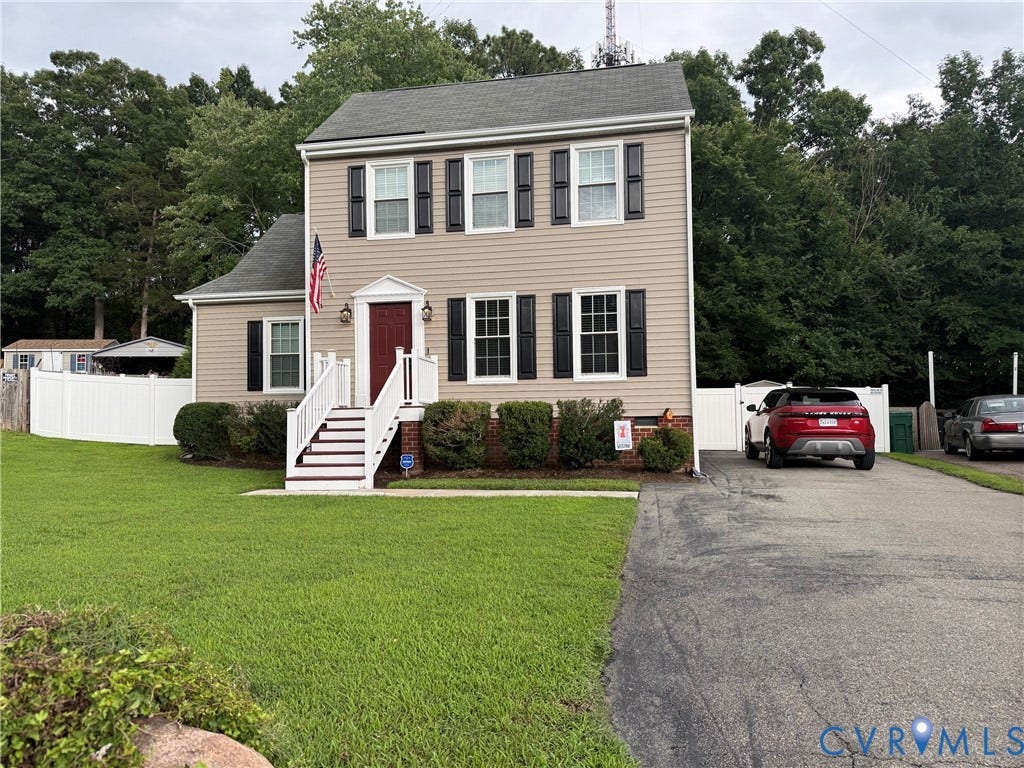 Two-story residence featuring light-toned siding, black louvered shutters, and a red front door