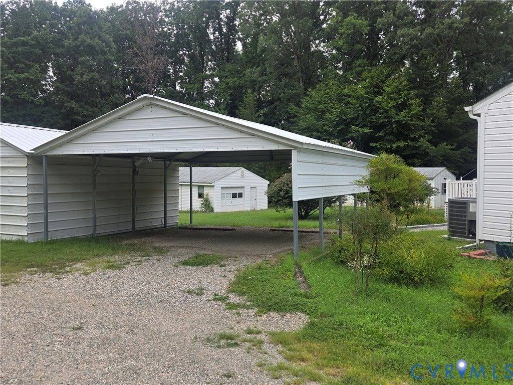 2311 Georges Road, Powhatan, VA 23139 Gravel driveway leading to a metal carport structure with an adjacent metal-sided building