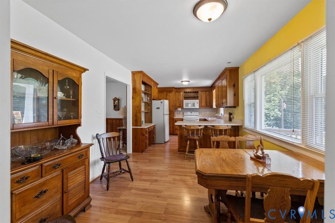 2311 Georges Road, Powhatan, VA 23139 Bright kitchen and dining area featuring wood-finish flooring, wood cabinetry, white countertops, and a large window with blinds