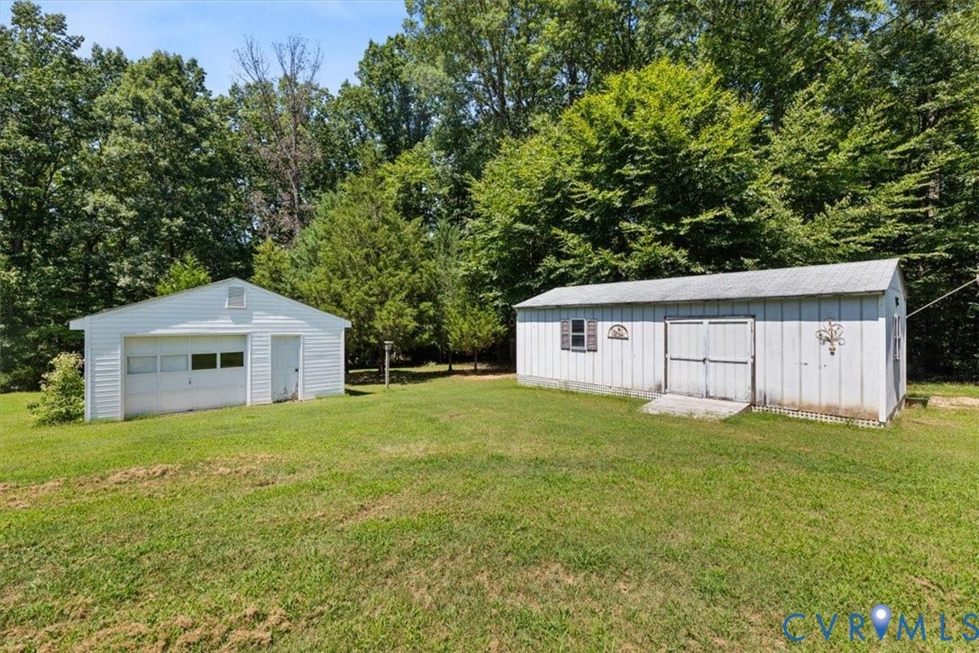 2311 Georges Road, Powhatan, VA 23139 Expansive green space featuring a detached garage with a roll-up door and a separate storage shed with double barn doors
