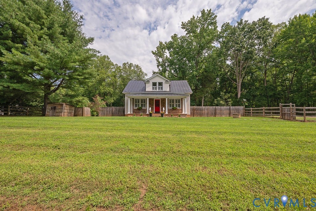 4808 River Road W Road, Goochland, VA 23063 Expansive grassy lawn with a cottage-style residence featuring a prominent red door, white columns, and a dark metal roof