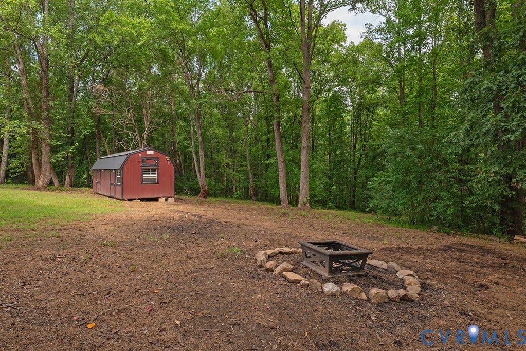 4808 River Road W Road, Goochland, VA 23063 Outdoor fire pit with stone surround and a red storage shed, backed by a dense treeline