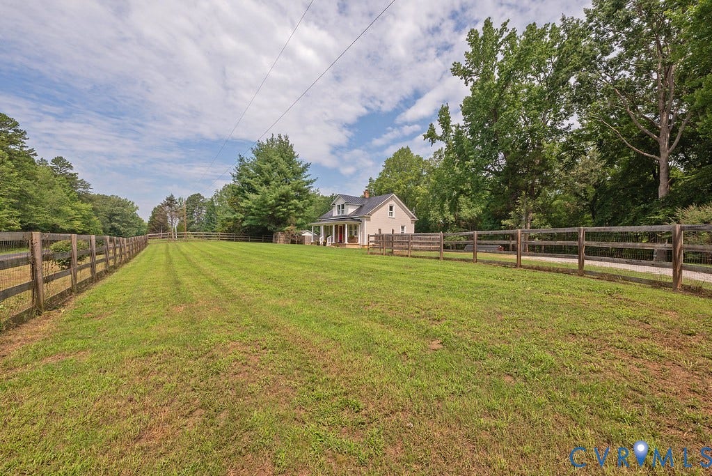 4808 River Road W Road, Goochland, VA 23063 Expansive green lawn bounded by a wooden split-rail fence, featuring a gravel driveway and mature trees
