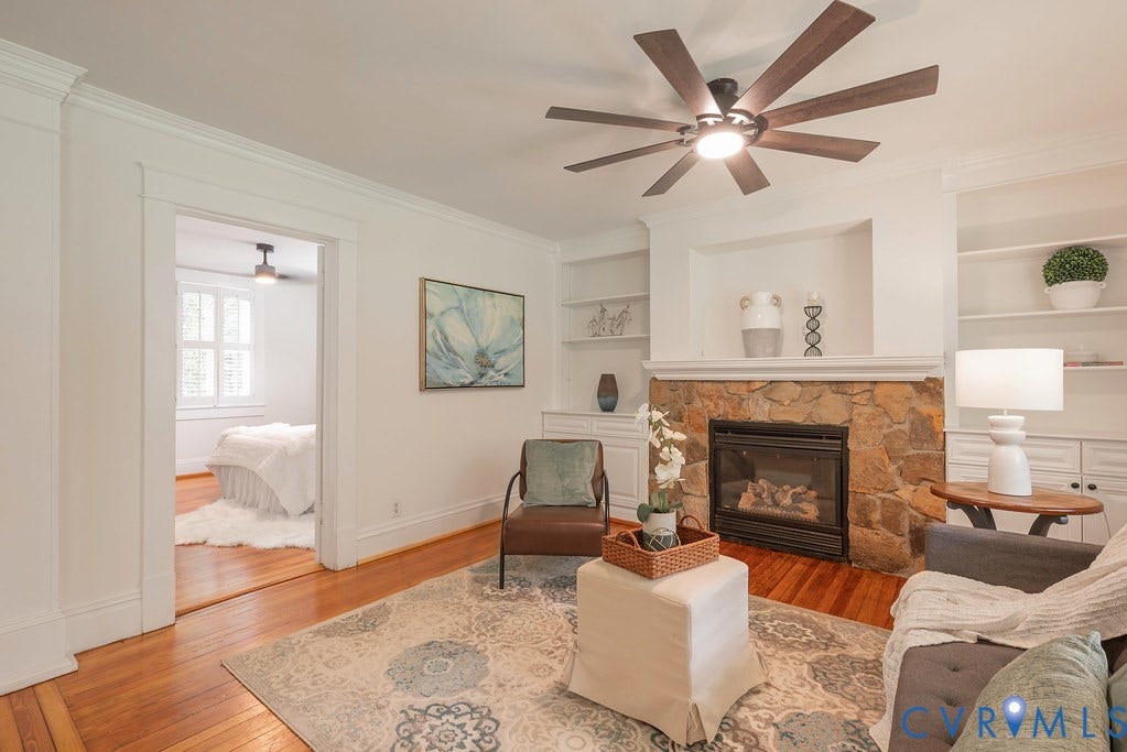 4808 River Road W Road, Goochland, VA 23063 Living space featuring a stone-clad fireplace with mantel, built-in shelving, wood-finish flooring, and a ceiling fan with integrated lighting