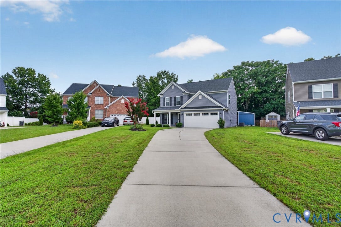 311 Cardinal Road, Countryside, Louisa, VA 23093 Gray two-story residence featuring a white garage door, black shutters, and mature front yard landscaping