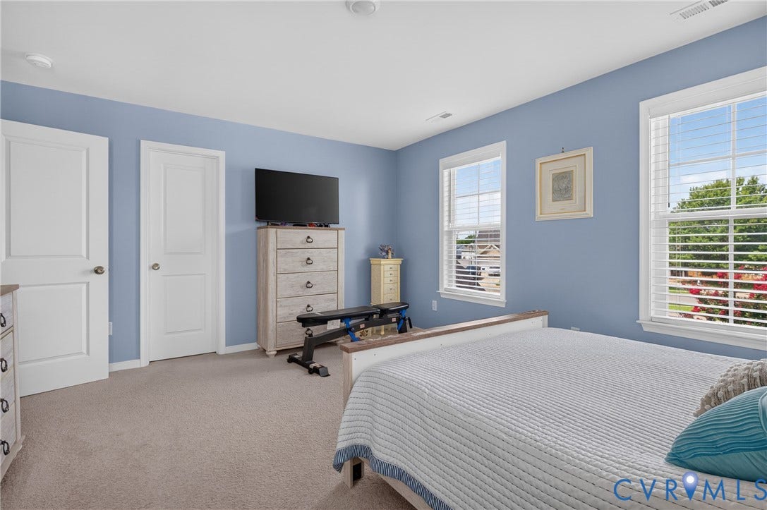 311 Cardinal Road, Countryside, Louisa, VA 23093 Carpeted bedroom featuring two paneled doors, two windows with white blinds, and light blue painted walls