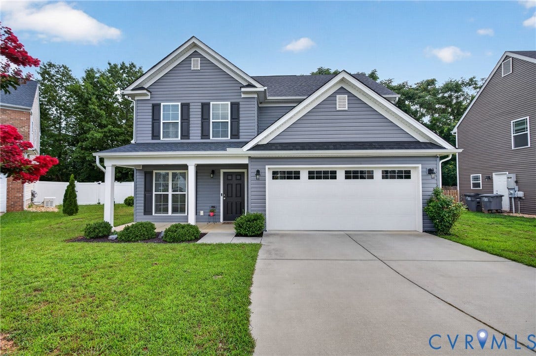 311 Cardinal Road, Countryside, Louisa, VA 23093 Two-story residential exterior featuring gray siding, a white columned front porch, a two-car garage with transom windows, and a concrete driveway