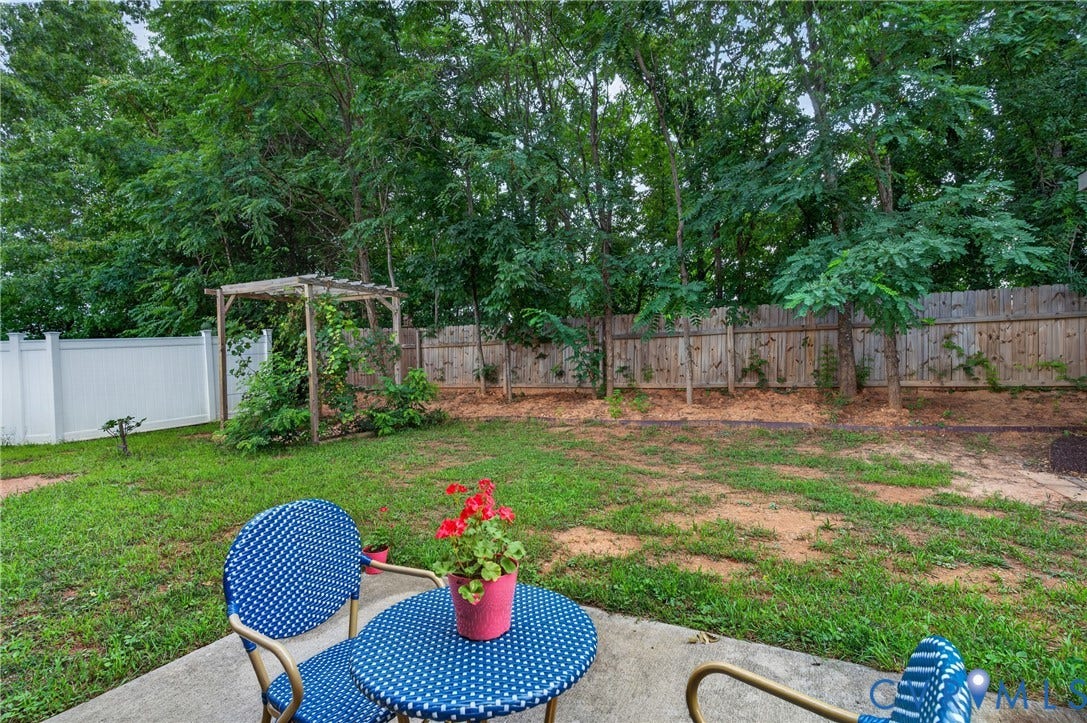 311 Cardinal Road, Countryside, Louisa, VA 23093 Expansive backyard featuring a concrete patio, a wooden pergola, a white vinyl privacy fence, and a natural wood privacy fence