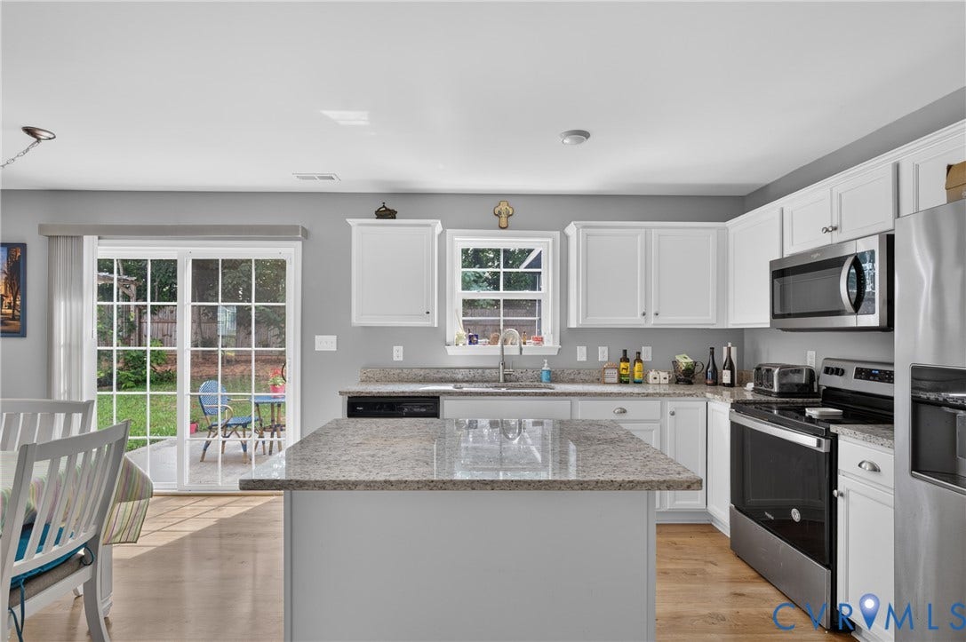 311 Cardinal Road, Countryside, Louisa, VA 23093 Kitchen featuring a central island with a granite-style countertop, white cabinetry, wood-finish flooring, stainless steel appliances, and sliding glass doors opening to the exterior patio