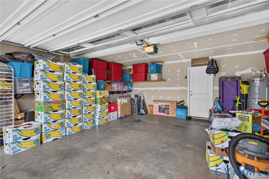311 Cardinal Road, Countryside, Louisa, VA 23093 Garage space featuring a roll-up overhead door, concrete flooring, interior access door, and wall-mounted shelving