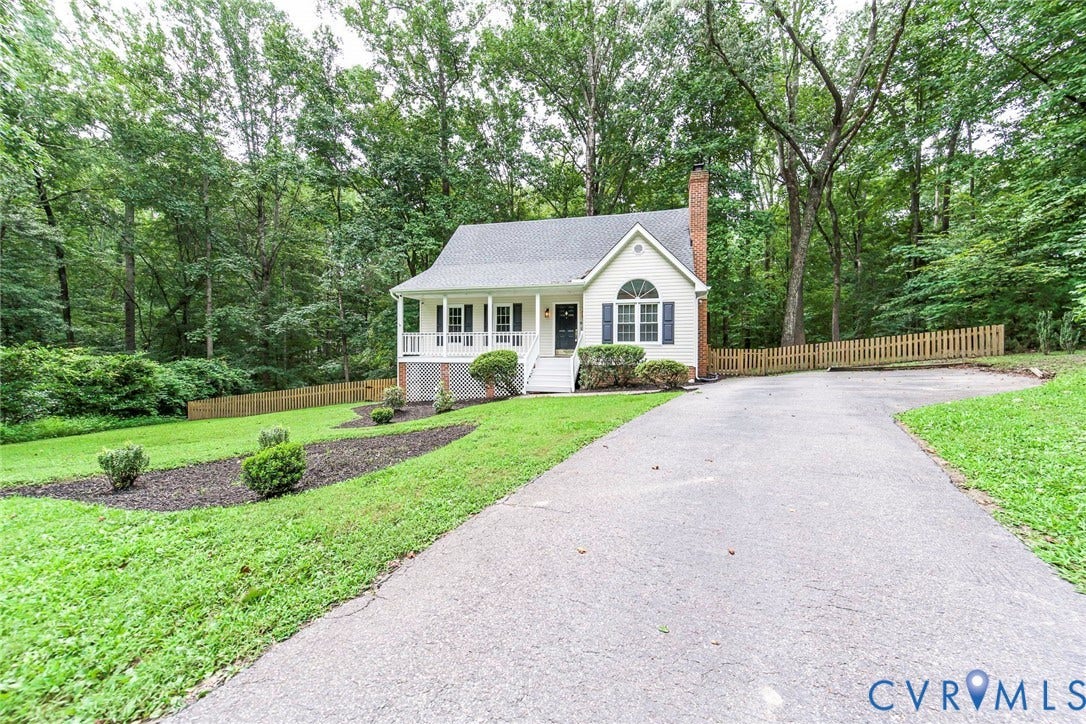 14001 Branched Antler Drive, Antler Ridge, Midlothian, VA 23112 White exterior with dark shutters, front porch with white railings, curved asphalt driveway, brick chimney, and sloped front lawn with landscape beds