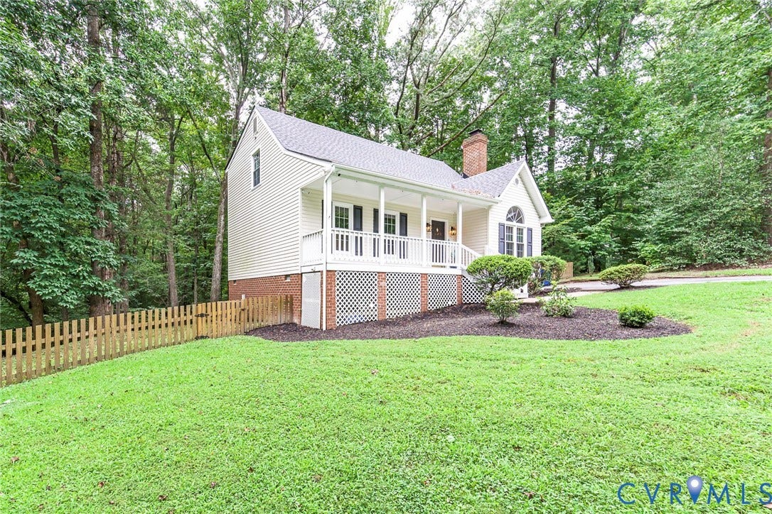14001 Branched Antler Drive, Antler Ridge, Midlothian, VA 23112 Wooded setting with a picket fence, white siding, brick foundation, front porch, and mature landscaping