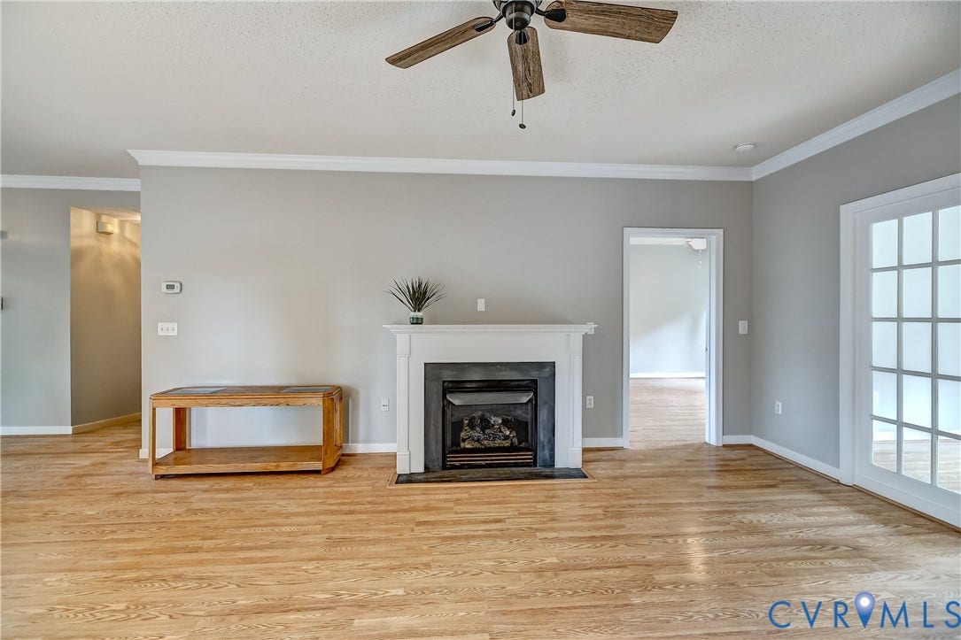 4602 Twin Hickory Lake Drive, Twin Hickory, Glen Allen, VA 23059 Spacious living area featuring gleaming wood-finish flooring, a ceiling fan with light fixture, and a gas fireplace with white surround and black hearth