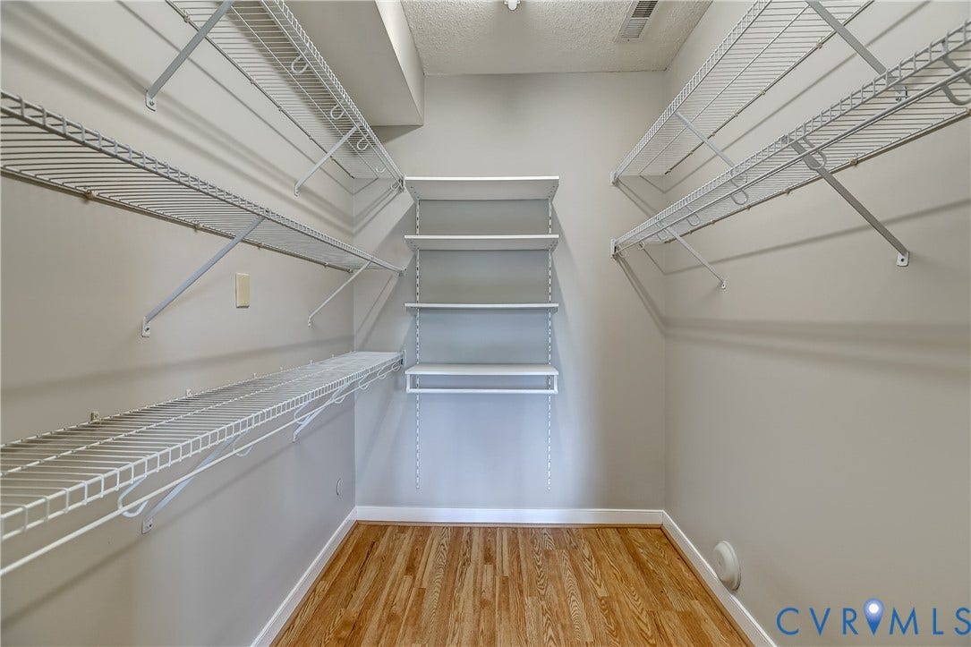 4602 Twin Hickory Lake Drive, Twin Hickory, Glen Allen, VA 23059 Spacious walk-in closet featuring extensive wire shelving systems on both sides, wood-finish flooring, and bright overhead lighting