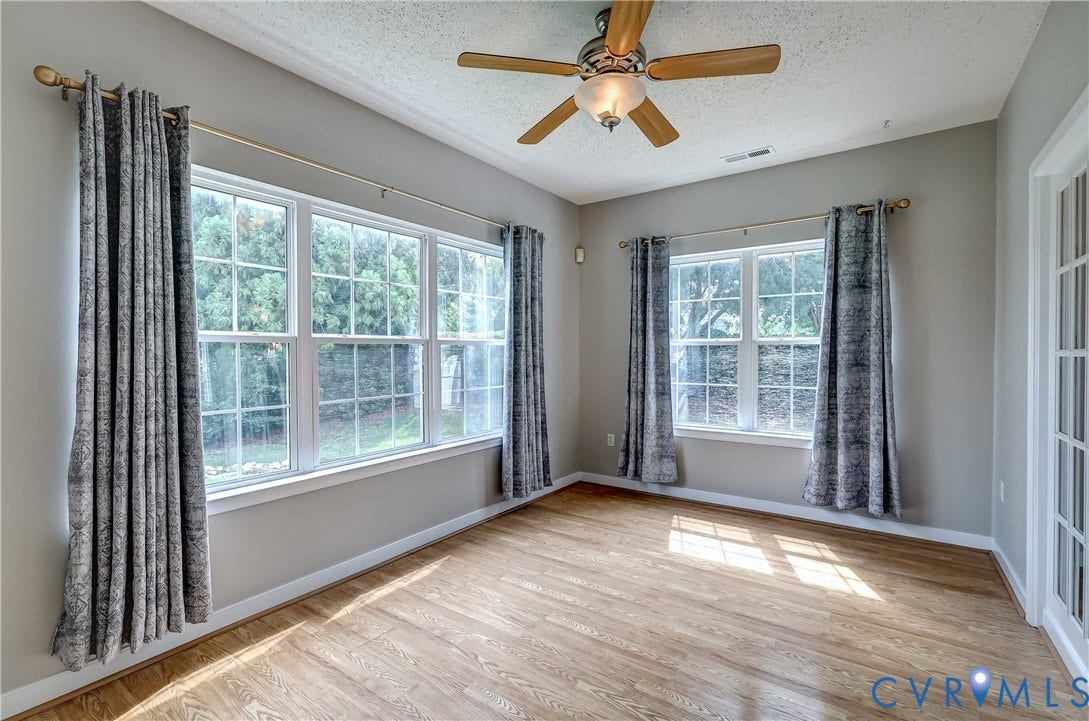 4602 Twin Hickory Lake Drive, Twin Hickory, Glen Allen, VA 23059 Sunlit bonus room showcasing abundant natural light through dual multi-pane windows, hardwood flooring throughout, ceiling fan with integrated lighting, and neutral wall finishes