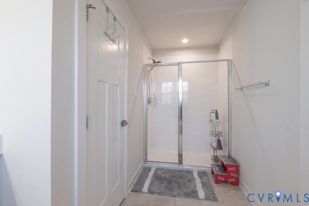 10419 Centralia Station Road, Chester, VA 23831 Shower enclosure with clear glass doors and chrome framing, featuring white subway tile surround and a recessed ceiling light