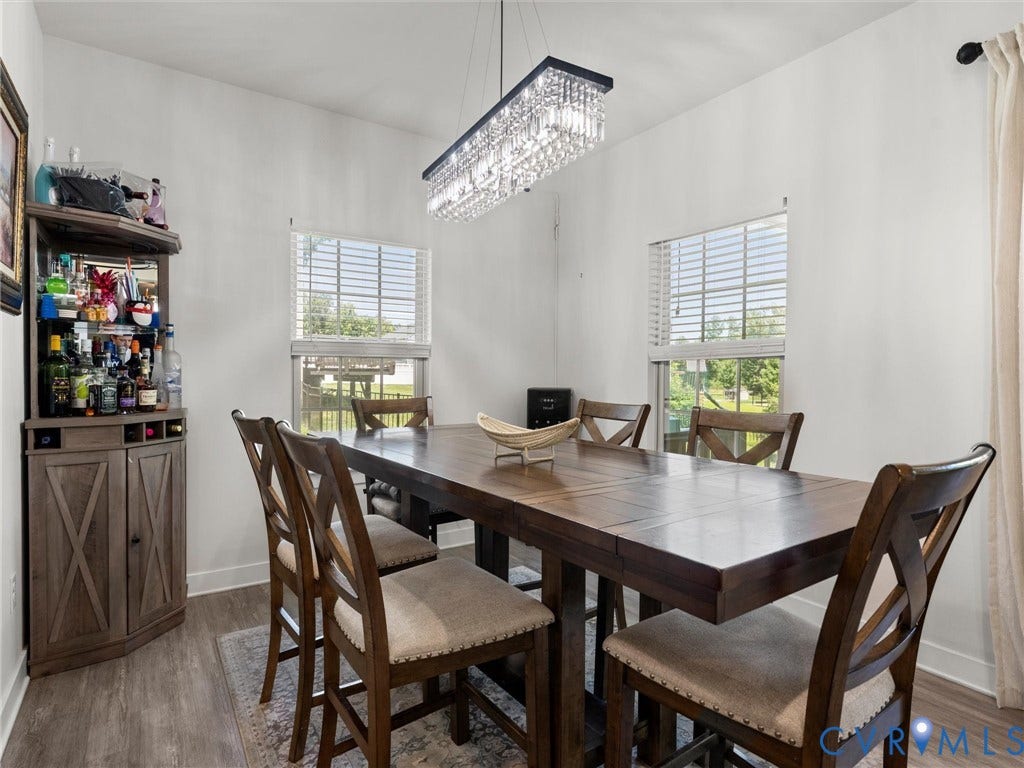 10419 Centralia Station Road, Chester, VA 23831 Dining area featuring wood-finish flooring, a linear crystal chandelier, and two windows with horizontal blinds