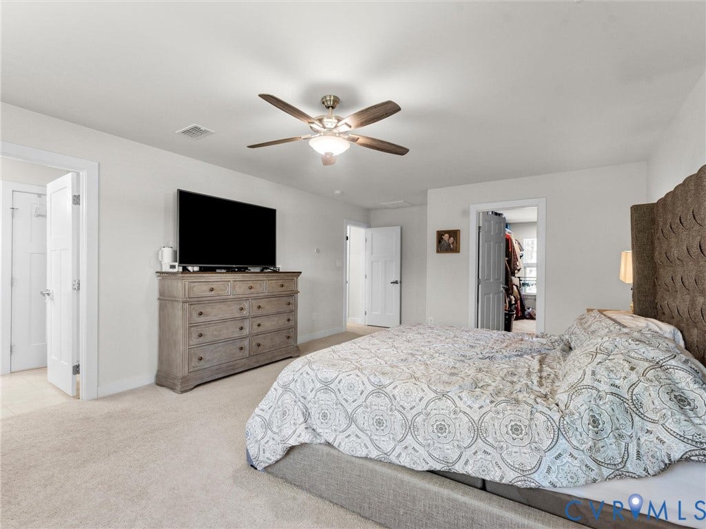 10419 Centralia Station Road, Chester, VA 23831 Spacious bedroom featuring plush carpeting, a ceiling fan with integrated lighting, and multiple doorways providing access to additional areas