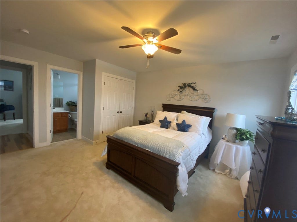 3267 Bayberry Lane, Goochland, VA 23063 Carpeted bedroom featuring a ceiling fan with integrated lighting, double bi-fold closet doors, and access to a full bathroom with a wood-finish vanity