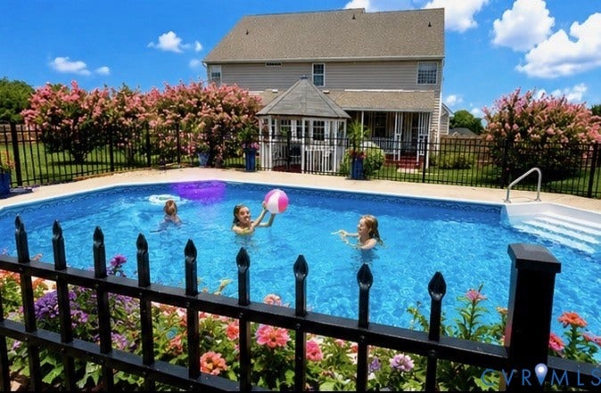 3267 Bayberry Lane, Goochland, VA 23063 Backyard features a large in-ground swimming pool with integrated steps, surrounded by a black wrought iron fence