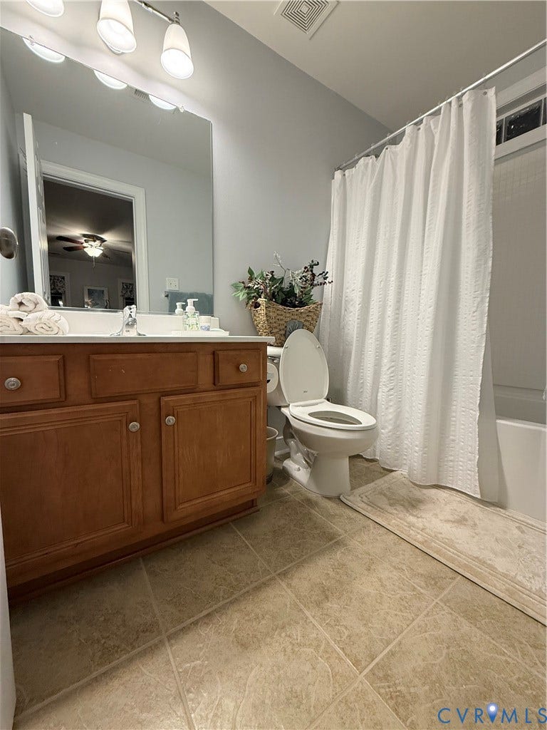 3267 Bayberry Lane, Goochland, VA 23063 Bathroom featuring a wood-finish vanity with a double-basin sink, large wall mirror, and a full bathtub with an overhead shower