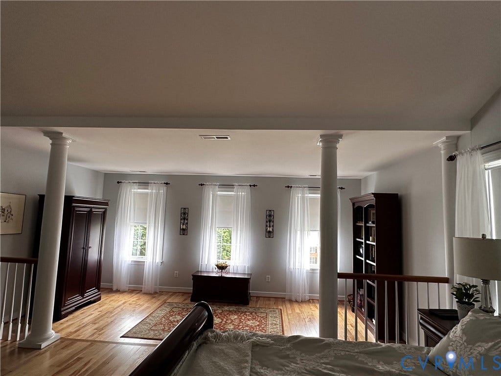 3267 Bayberry Lane, Goochland, VA 23063 Light-filled open space featuring decorative columns, light wood-finish flooring, and multiple windows with sheer white drapery
