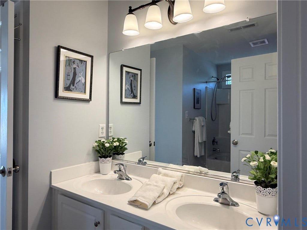 3267 Bayberry Lane, Goochland, VA 23063 Dual vanity with integrated sinks, white cabinetry, chrome fixtures, and a large wall-mounted mirror