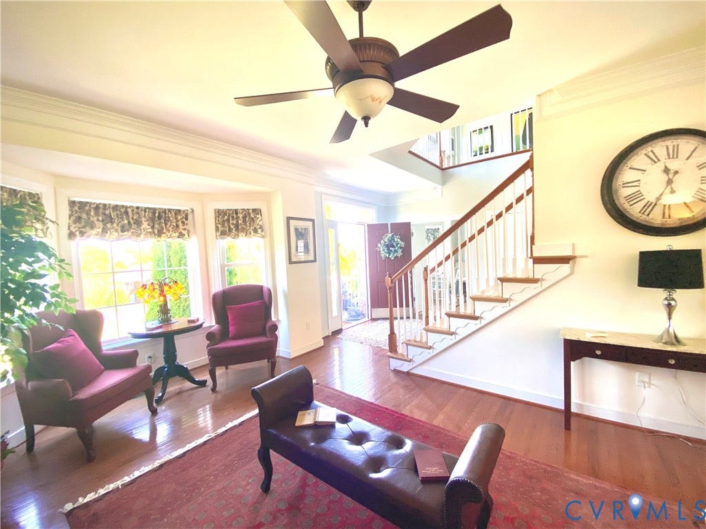 3267 Bayberry Lane, Goochland, VA 23063 Foyer featuring hardwood flooring, a multi-paneled front door, a staircase with white balusters and wood handrails, a bay window, and a ceiling fan