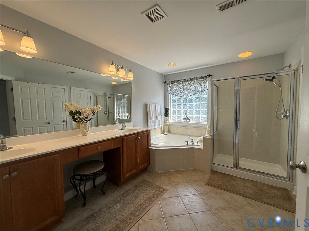 3267 Bayberry Lane, Goochland, VA 23063 Spacious bathroom featuring an expansive double vanity with integrated sinks, a built-in vanity desk, a corner soaking tub, and a glass-enclosed shower