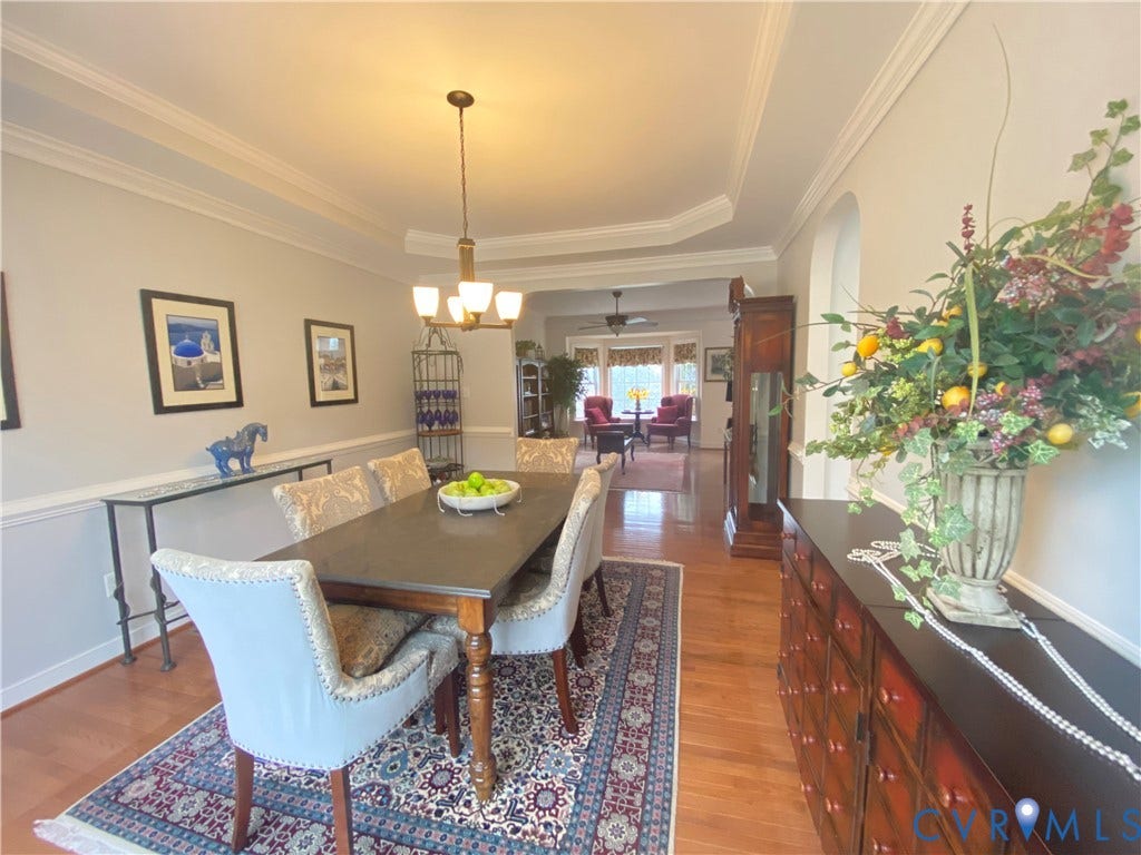 3267 Bayberry Lane, Goochland, VA 23063 Formal dining area featuring hardwood flooring, a tray ceiling, crown molding, chair rail, and an archway leading to an additional living space