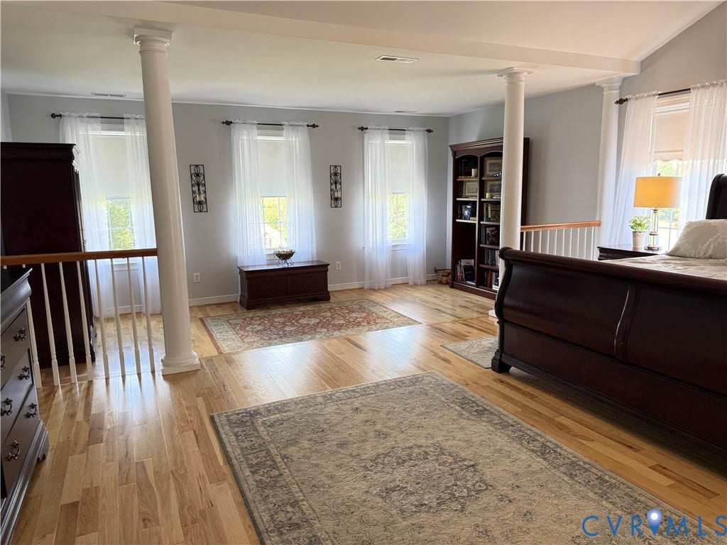 3267 Bayberry Lane, Goochland, VA 23063 Spacious room featuring light wood-finish flooring, multiple windows with sheers, and architectural columns