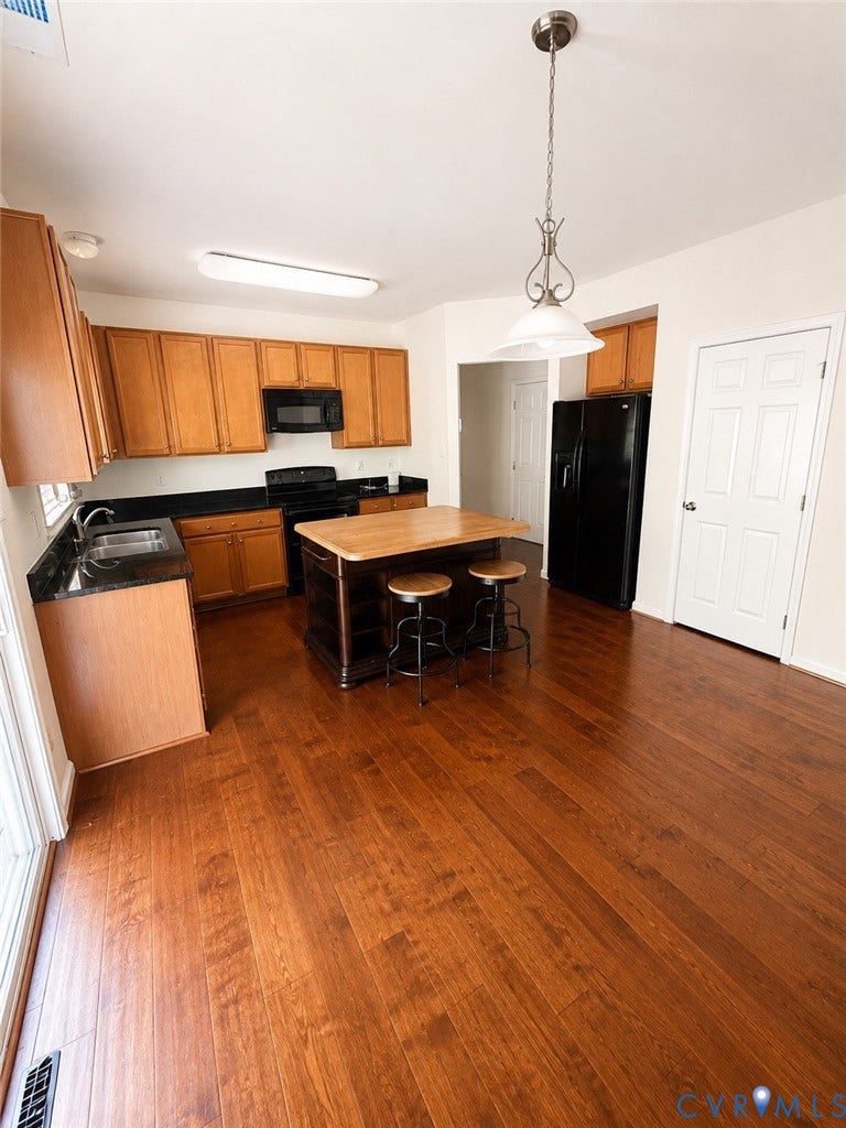 2312 Thomas Kenney Drive, Glen Allen, VA 23060 Kitchen featuring wood-finish flooring, dark granite-style countertops, wood cabinetry, and a central island with a wood-finish top