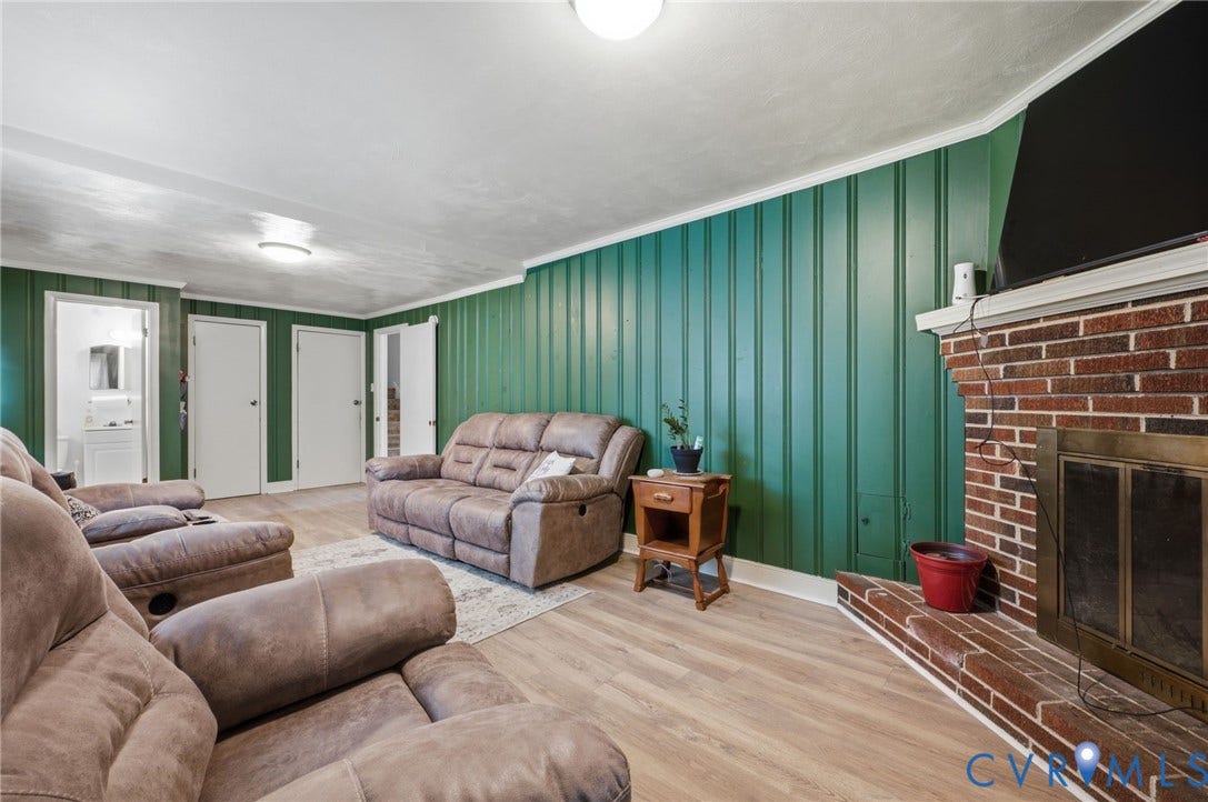 4021 Beulah Road, Chesterfield, VA 23237 Living area featuring wood-finish flooring, a brick fireplace with a brass-toned insert, and paneling on the walls
