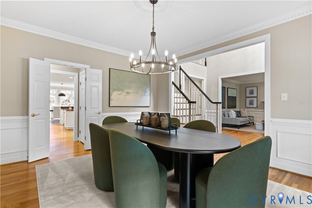 Dining area featuring wood-finish flooring, wainscoting, crown molding, and modern a chandelier