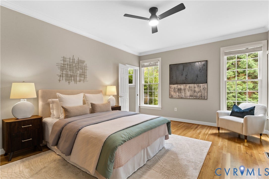 Spacious first floor bedroom suite featuring wood-finish flooring, crown molding, and a ceiling fan