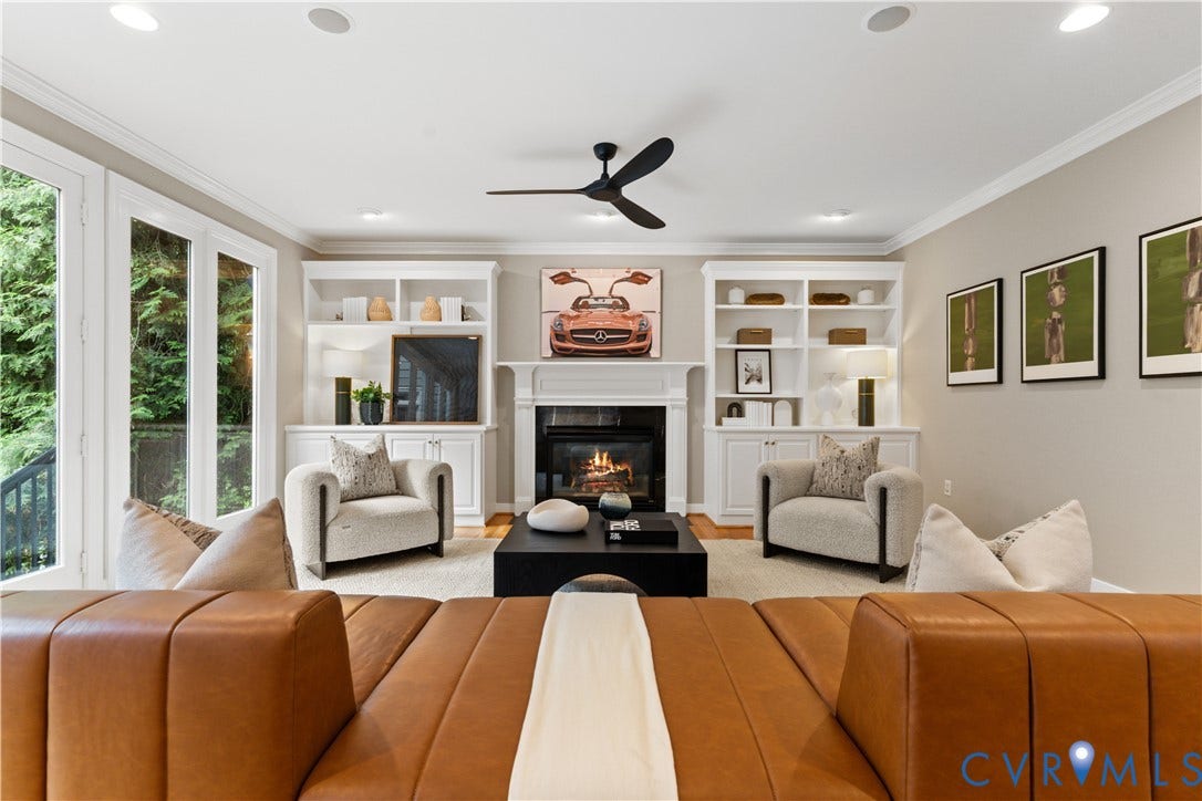 Living area featuring a fireplace with a white mantel, flanked by built-in shelving and cabinetry