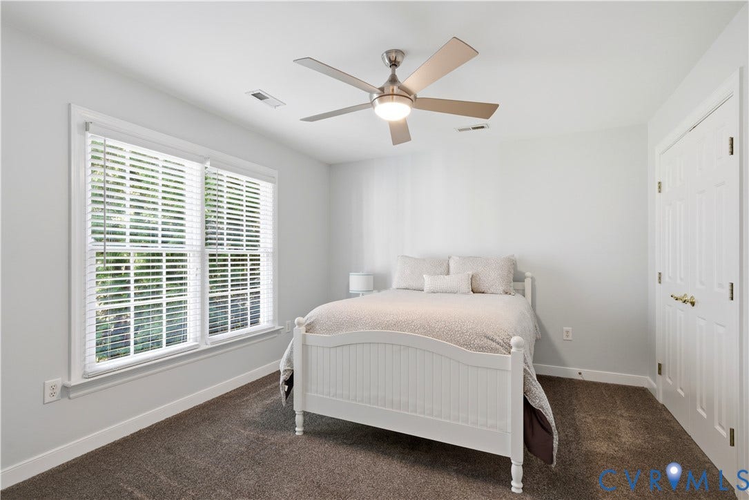 Bedroom featuring light gray walls, plush brown carpeting, and a ceiling fan with integrated lighting