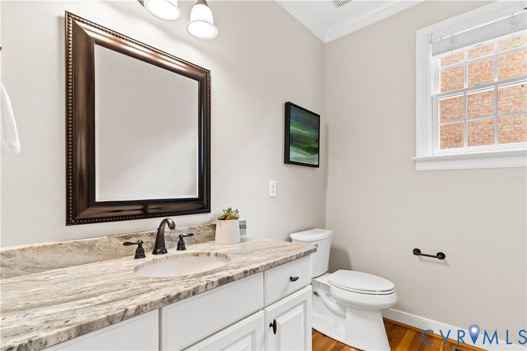 Bathroom vanity featuring a light-toned stone countertop with an undermount sink and oil-rubbed bronze faucet