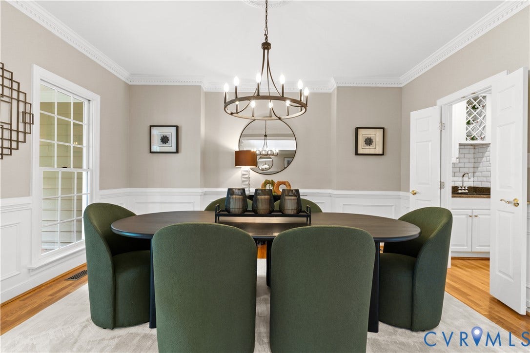 Dining room with gorgeous, modern chandelier, hardwood floors, wainscoting, and crown molding