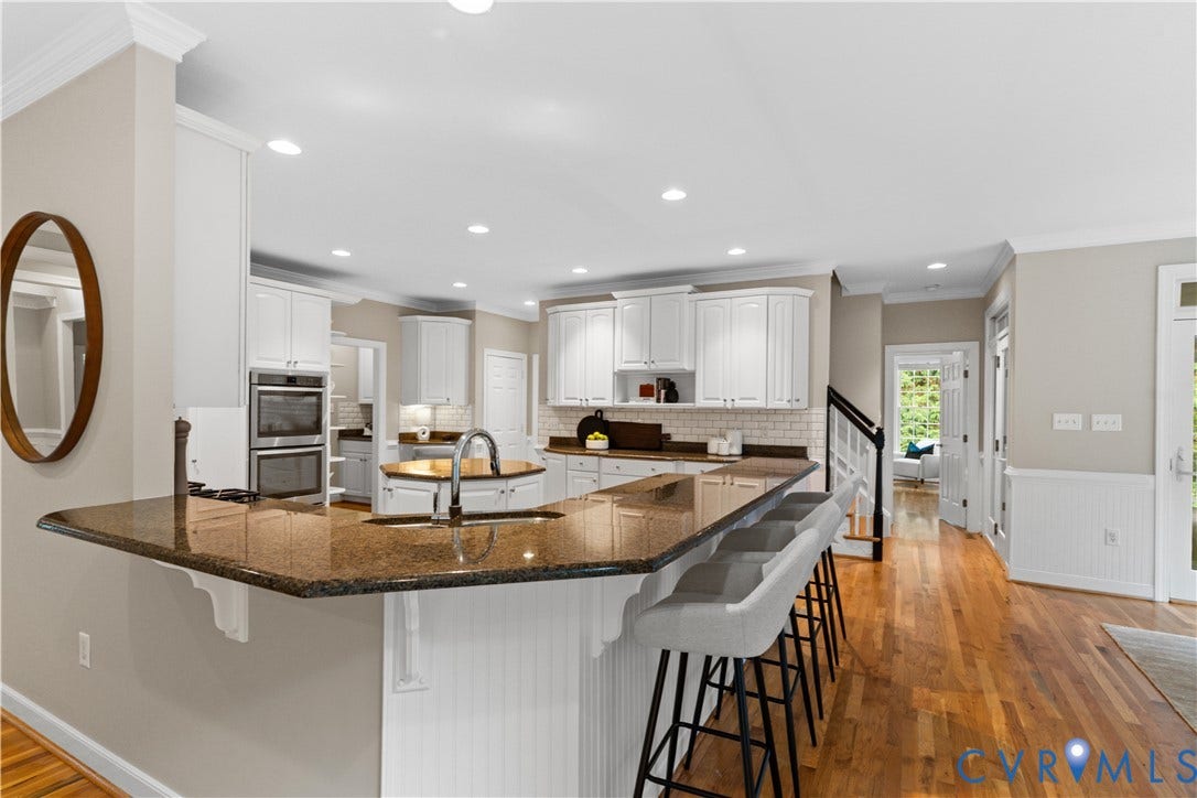 Kitchen with white cabinetry, a large central island with a sink, recessed lighting, and wood-finish flooring