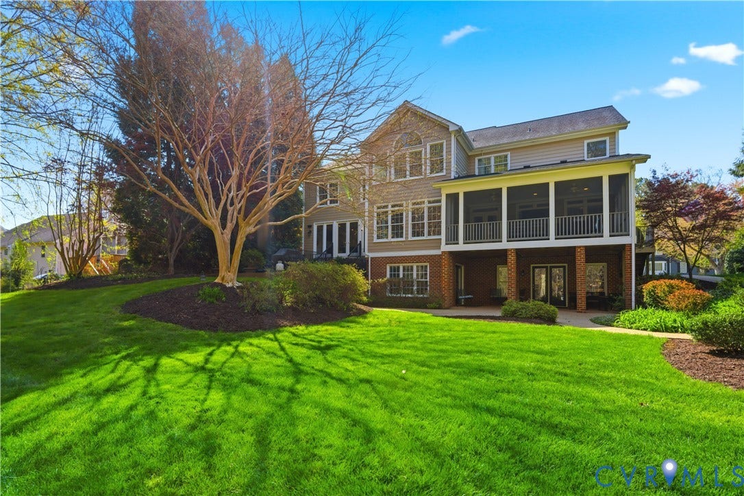 Expansive rear exterior featuring a screened-in porch, multiple windows, and a lower-level patio with double doors