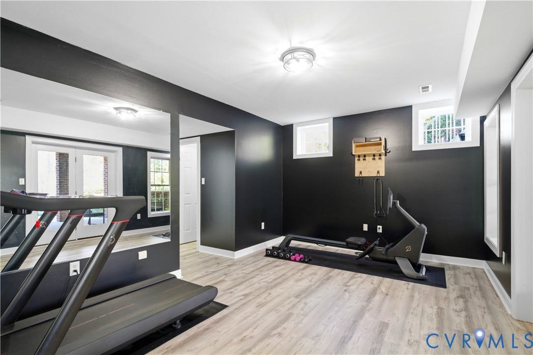 Recreation room featuring wood-finish flooring, recessed lighting, multiple windows, and a full-length mirrored wall
