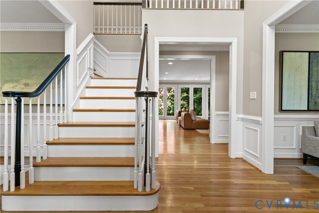 Grand foyer featuring a curved staircase with wood treads and white risers, framed by white balusters and dark wood handrails