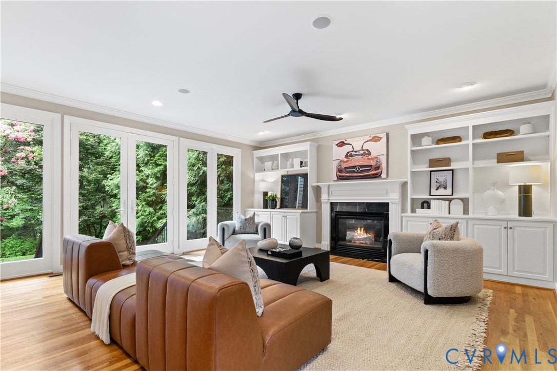 Spacious living area featuring extensive built-in shelving, a central fireplace with a dark surround, and hardwood flooring