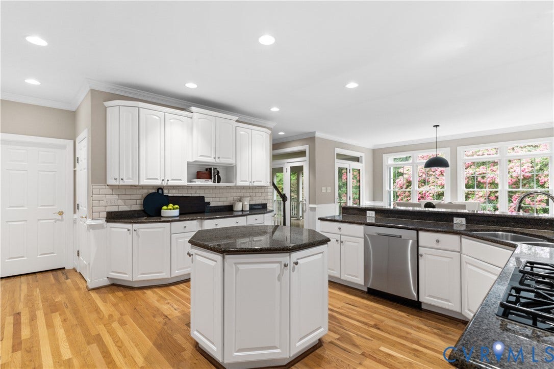 Kitchen featuring white cabinetry, dark countertops, a hexagonal island, wood-finish flooring, and recessed lighting