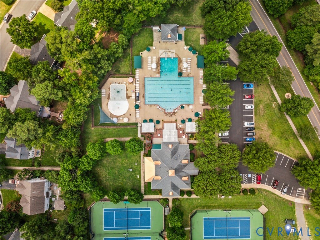 Expansive recreational area featuring a large swimming pool, an additional smaller pool, multiple tennis courts, a central clubhouse, and ample parking
