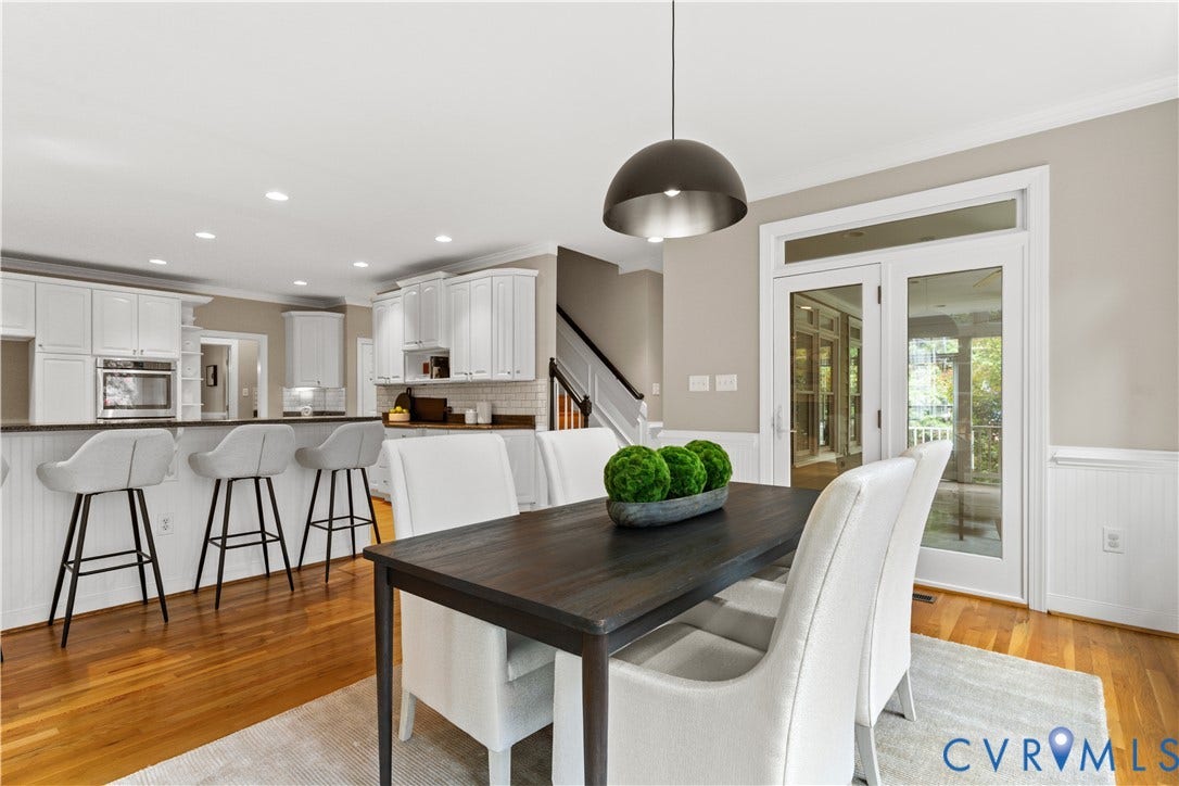 Open-concept living space featuring hardwood flooring, white paneled wainscoting, and recessed lighting