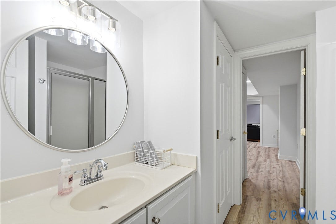 Bathroom vanity with a round mirror, chrome faucet, and integrated sink