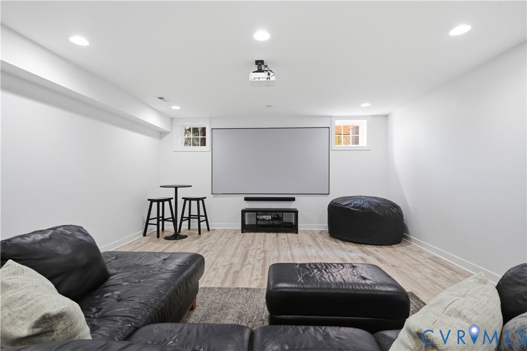 Entertainment space with a large projection screen, recessed lighting, and wood-finish flooring (LVP)